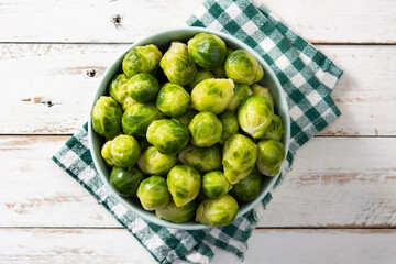 Set of brussel sprouts in a bowl on white wooden table. Top view