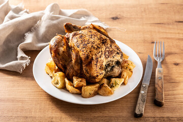 Homemade roasted chicken with potatoes on wooden table