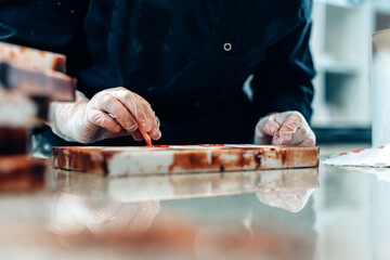 close up on hands of a pastry chef decorating white chocolates in an artisanal workshop