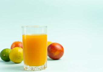 Glass of yellow juice with fruits on a blue background