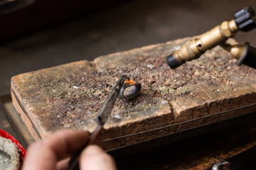 goldsmith jeweler soldering a silver ring on the workbench with a soldering.