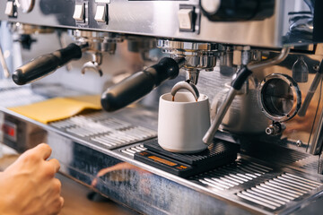 Coffee extraction on espresso machine in the red cup. Close-up of espresso pouring from coffee machine.