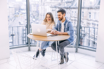 Beautiful couple working on a laptop in a cafe. Happy young man