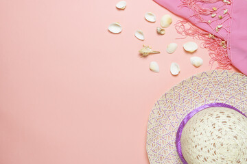 Female straw hat and seashells on light pink  background. Summer holidays concept.