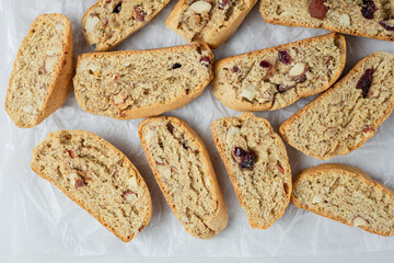 Italian biscotti cookies on baking paper. Top view fresh baked cookies with nuts and dried cranberries. Vegan recipe