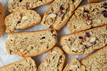 Italian biscotti cookies on baking paper. Top view fresh baked cookies with nuts and dried cranberries. Vegan recipe
