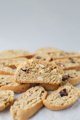 Close up Italian biscotti cookies on baking paper. Fresh baked cookies with nuts and dried cranberries with selective focus. Vertical orientation