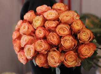 Young woman with a gift bouquet of orange roses, mono bouquet of roses. Young woman holding fresh...