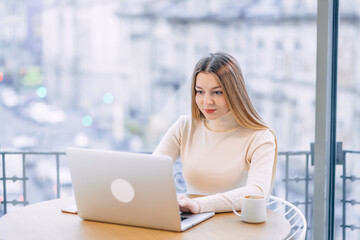 Concentrated young business woman or student looking at laptop h