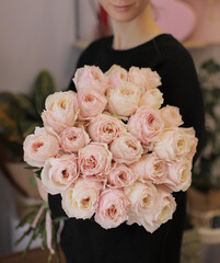 Young woman with a gift bouquet of pink roses, mono bouquet of peonies roses. Young woman holding fresh bouquet of roses.