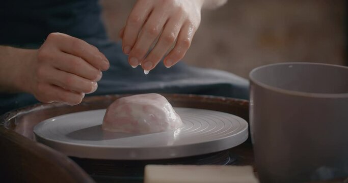 Potter wets piece of colored clay on the potter's wheel for sculpting ceramics in nerikomi style, neriage ceramics, potter makes ceramics in slow motion, 4k 60p Prores HQ 10 bit