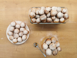 Small cottage cheese balls. Freshly made cottage cheese donuts sprinkled with powdered sugar on a wooden table top. Profiteroles.