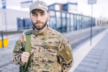 Fototapeta premium a serious young soldier standing in the street, wearing a cap an