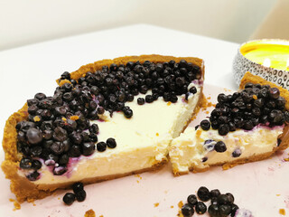 Simple classic New York cheesecake with sliced blueberries on a tabletop with a candle background. Close-up cake. Cozy evening in the kitchen