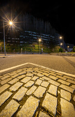 Cobblestone triangle covered by white lines and in the background the line of car lights