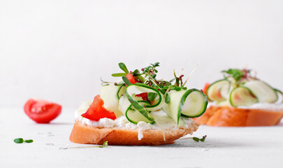 Vegetarian bruschetta with cream cheese, cucumber, pepper, tomato and microgreen on the white table