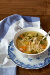 Chicken soup on a white napkin with blue stripes. Side view.