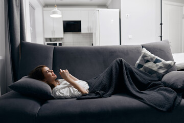 young woman in white t-shirt lies on the sofa indoors