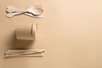 Eco-friendly biodegradable disposable paper cups, individual wooden spoons, forks, bamboo straws on...