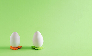 Easter egg with green and orange   legs . Minimal holiday concept on green background with copy space.