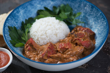 Closeup of indian butter chicken or murgh makhani served in a blue bowl, selective focus, studio shot
