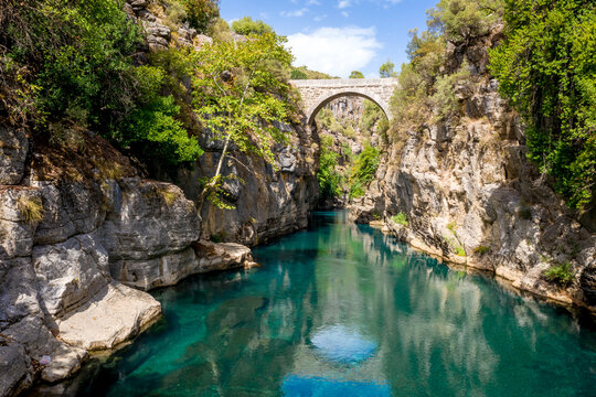 Ancient arch bridge Oluk over the Koprucay river gorge in Koprulu national Park in Turkey. Panoramic scenic view of the canyon and blue stormy mountain river
