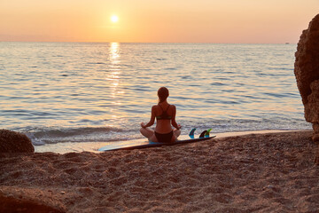 Fototapeta na wymiar Meditation on beach at sunset. Woman practicing yoga on seashore. Relax in nature. Contemplation and meditation idea