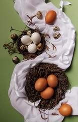 Still life with chicken and quail eggs lying in the nests. Birch branches with earrings. On the...