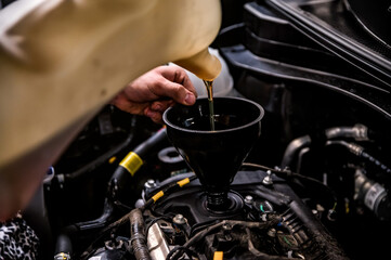 Close-up of mechanic adding oil with a funnel