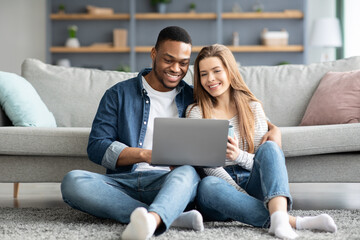 Happy Young Multicultural Couple Relaxing With Laptop On Floor At Home