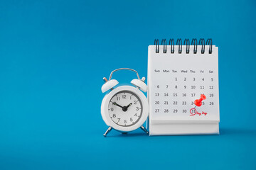 red thumbtack pin on the last day  of month with circle and pay day word near white analog clock on...