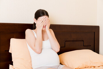 Young pretty pregnant woman suffering from headache at home in bed