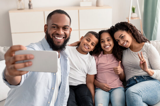 Portrait of black family taking selfie together at home