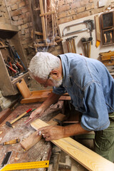 Experienced carpenter working in his old fashioned workshop.Working with sand paper.