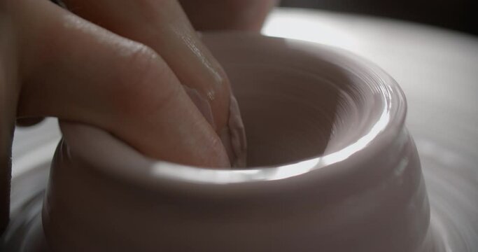 Close up view: potter sculpts a jug from red clay on a potter's wheel, pottery workshop, potter makes ceramics in slow motion, 4k 60p Prores HQ 10 bit