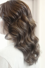 Naklejka premium light brown long curly loose hair closeup photo in hair salon back view