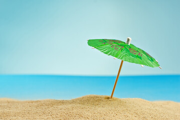 Beach umbrellas on the sand. Stylized cardboard beach. Paper umbrellas for cocktails in the background. The concept of rest, sea and vacation.