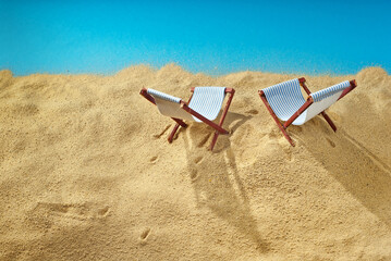 Beach chairs on the sand. Stylized cardboard beach. The concept of rest, sea and vacation. Artificial wooden deck chairs.