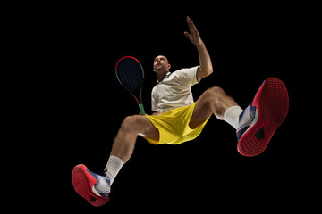 Young caucasian tennis player in action, motion isolated on black background, look from the bottom....
