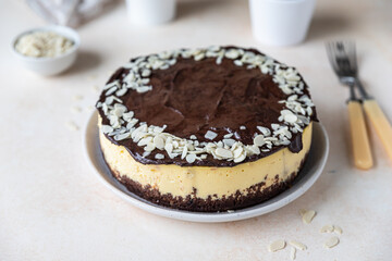 Delicious creamy cheesecake decorated with chocolate glaze and almond, light concrete background. No bake mousse dessert.