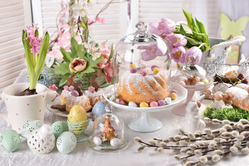 Fototapeta na wymiar Easter table with ring cake and decors under a glass cloche