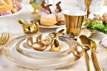 Easter table setting with golden color decors on the plate and cutlery