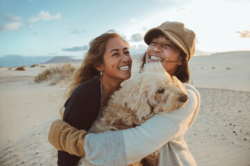 Two beautiful filipino women laughing and hugging each other and their dog