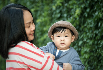Young asian mother hold little boy at green background