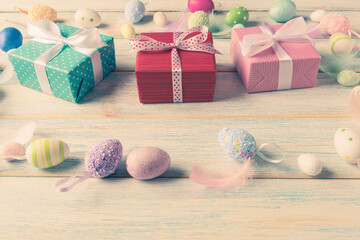 Fototapeta na wymiar Decorative Easter eggs and gift boxes on aged wooden background