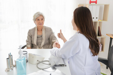 Obraz premium close up old patient, old Asian patient talk about treatment plan with female doctor in mental health clinic, doctor show thumb up sign with hand, elderly health check up, happiness hospital