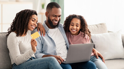 Black family using computer and credit card at home
