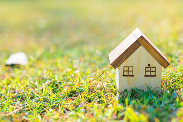 Wooden toy house model on green grass new home