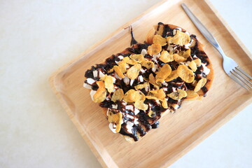 Toasts bread with cornflakes and chocolate on wooden table