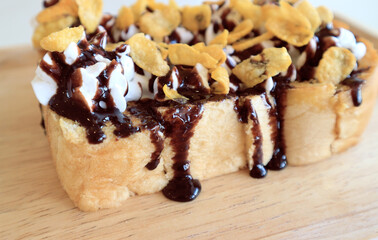 Toasts bread with cornflakes and chocolate on wooden table.